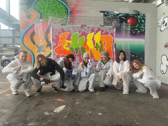 Gruppe posiert vor bunter Graffiti.