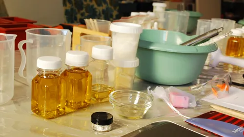 Bottles with liquid on cluttered crafting table.