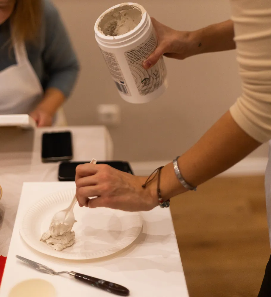 Person schöpft Ton auf Pappteller.