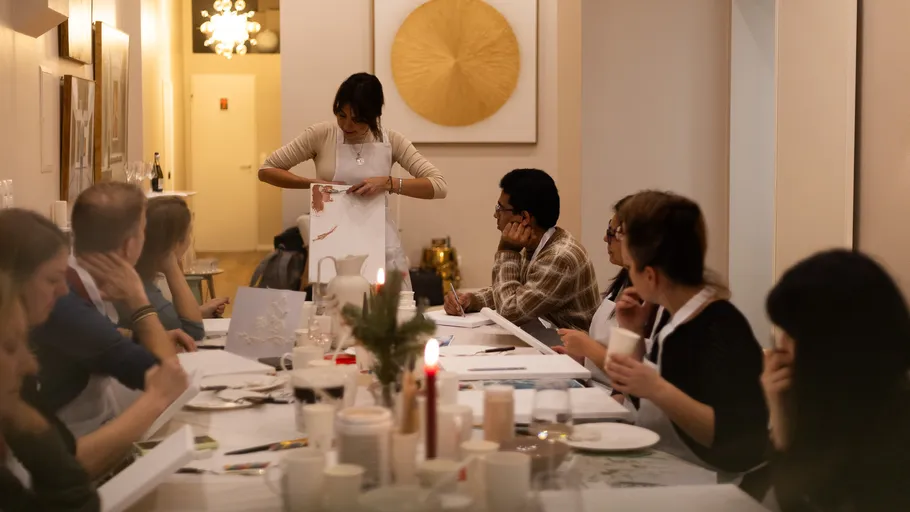 Personen sitzen an einem Tisch im Kunstkurs.