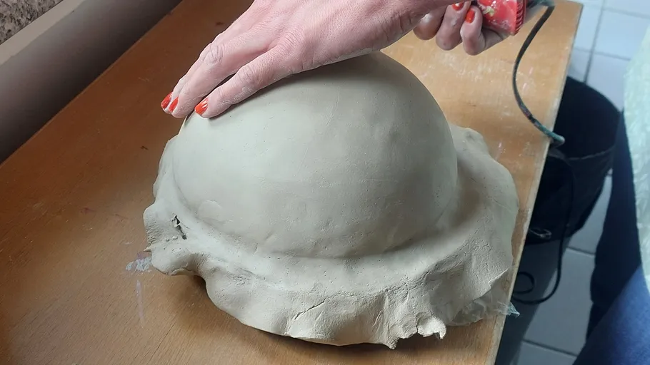 Hand formt Ton auf Holztisch.