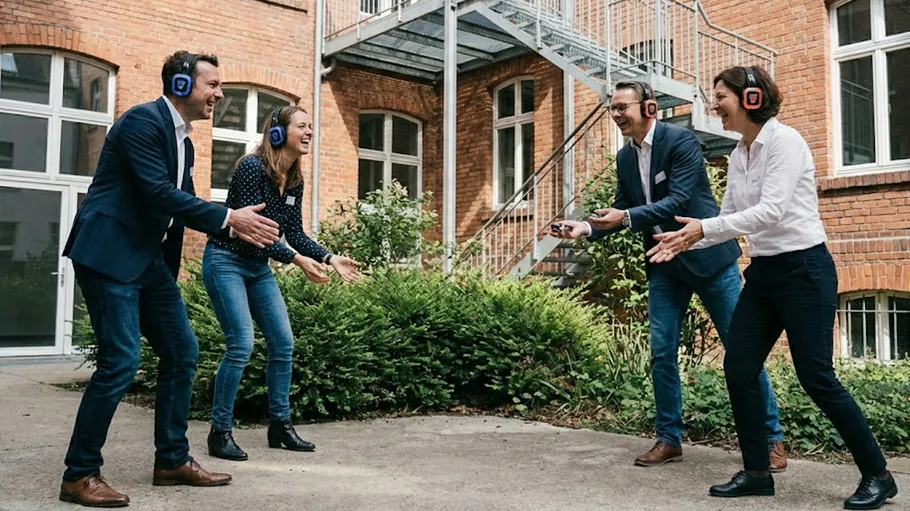 Four people playing a game with headphones outside.