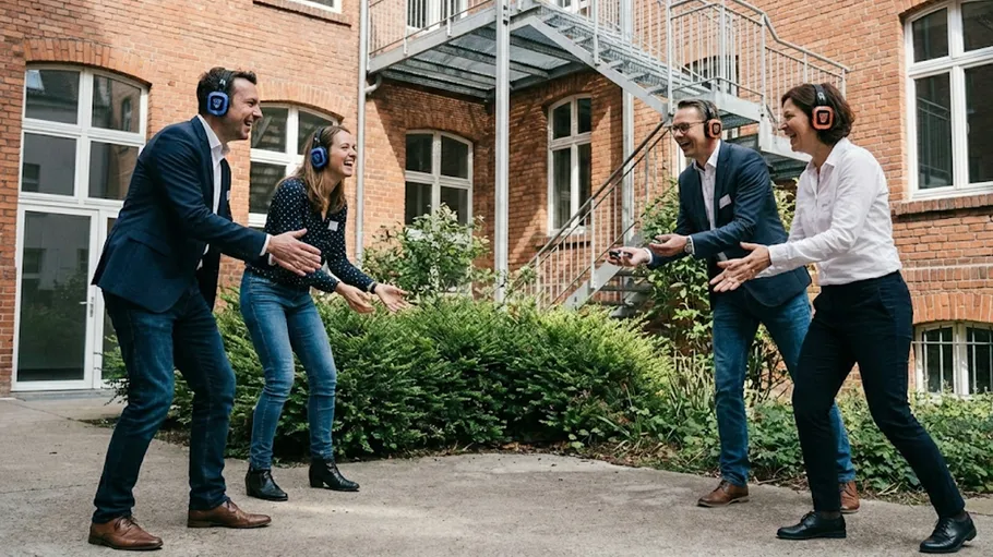 People wearing headphones playing catch outside.