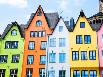 Colourful houses stand side by side under blue skies.