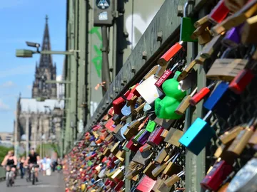Love locks hang on a bridge, with church in the background.