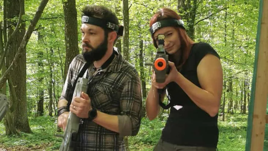 Zwei Personen spielen Lasertag im Wald.