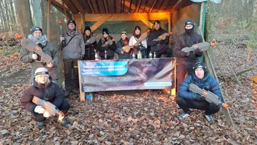 Group holding laser guns outdoors in forest.