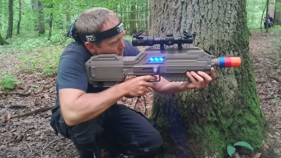 Mann zielt mit Lasertag-Gewehr im Wald.