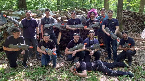 Gruppe mit Spielzeugwaffen im Wald, lächelnd.