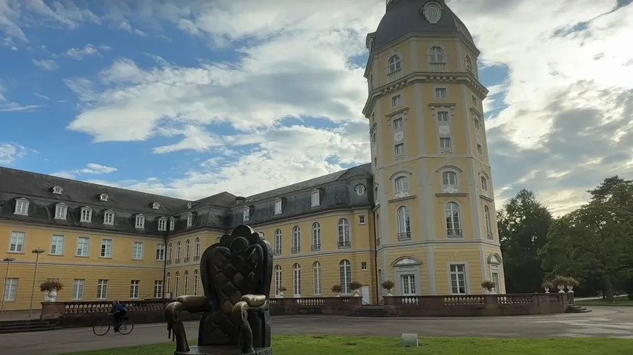 Gelbes Schloss mit Skulptur, blauer Himmel.