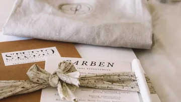 Wrapped stationery with pamphlet and pen on desk.