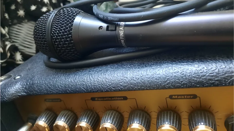 Microphone resting on amplifier with knobs.