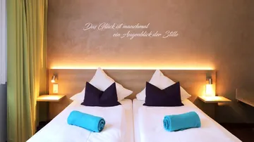 Zwei Betten mit Kissen, von hinten beleuchtet.