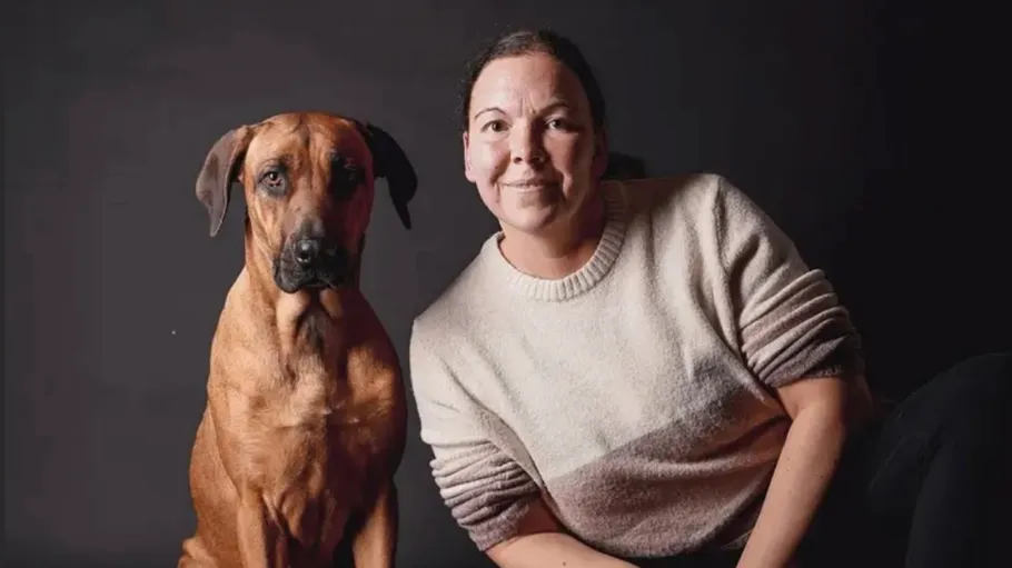 Person and dog sitting against dark background.
