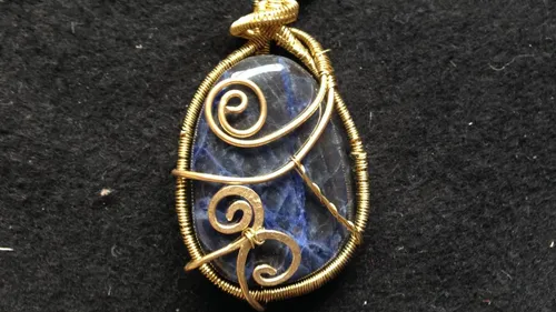 Blue gemstone pendant with gold wire wrapping.