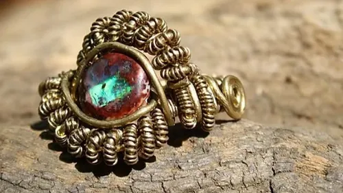 Intricate wire-wrapped gemstone ring on wood.