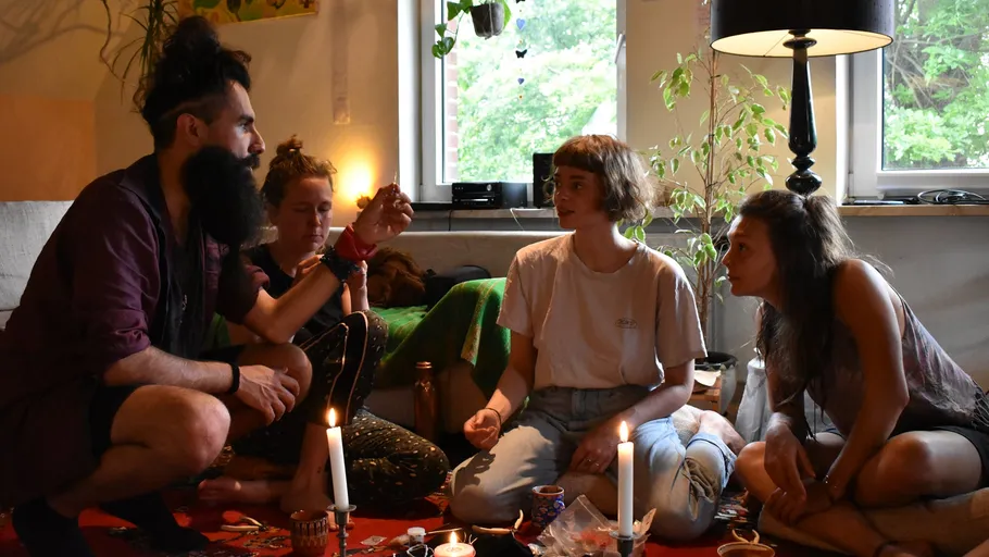 Group seated on floor around candles indoors.