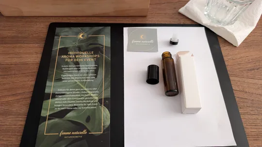 Workshop-Flyer mit Parfümflasche auf Tisch.