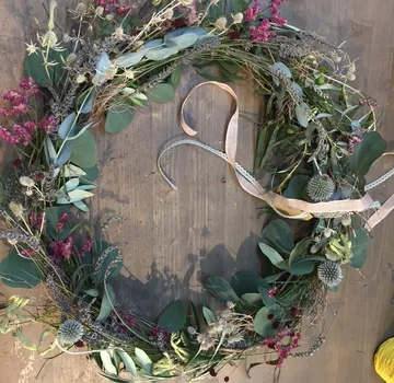Blumenkranz mit Band auf Holztisch.