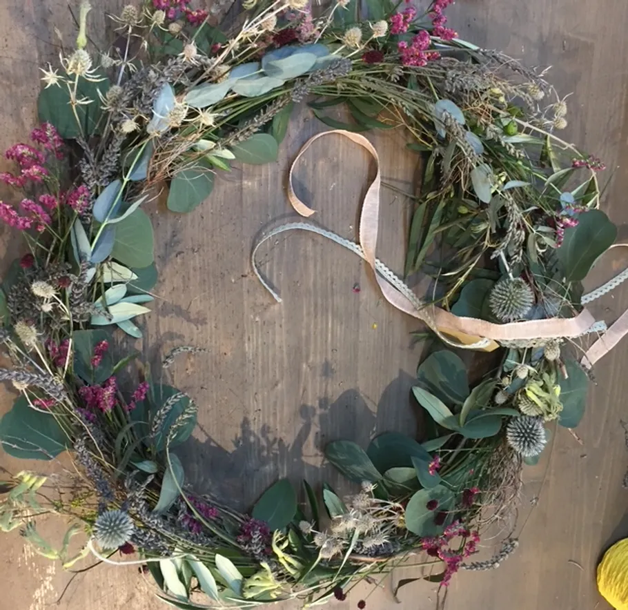 Floral wreath with ribbon on wooden table.