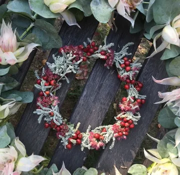 Blumenkranz auf Holzbänken mit Laubwerk.