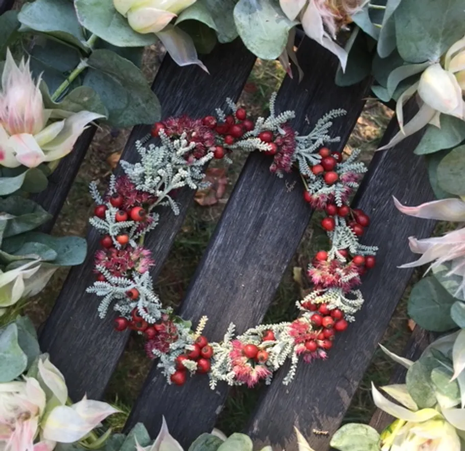 Floral wreath on wooden bench with foliage.