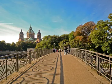 Bridge with walkers, view of a church in the background.