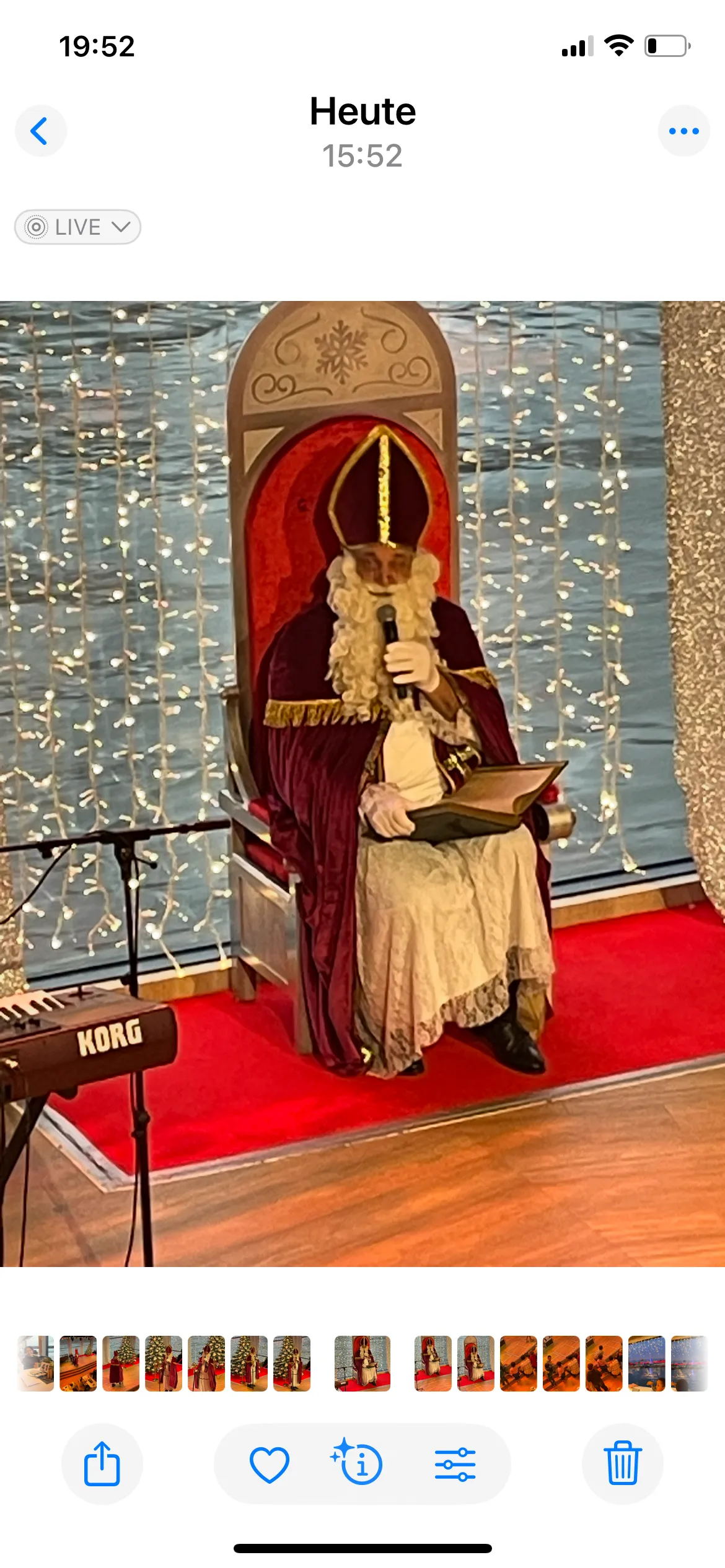 Figur liest auf Thron, festliche Lichter im Hintergrund.