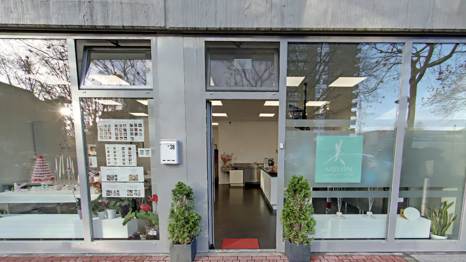Storefront with glass windows and plants outside.