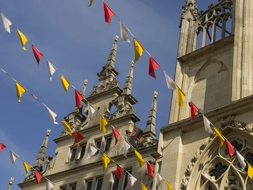 Flags hang on a historic building under a blue sky.