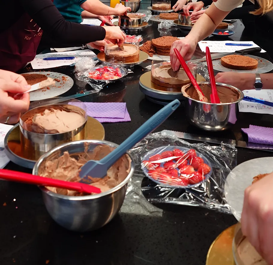 People decorating cakes with chocolate frosting.