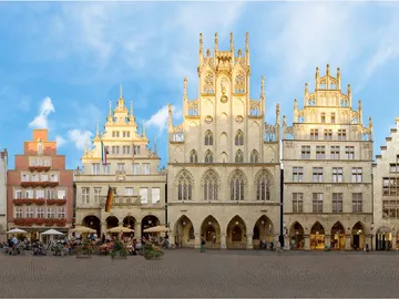 Four historic buildings stand in a lively square.