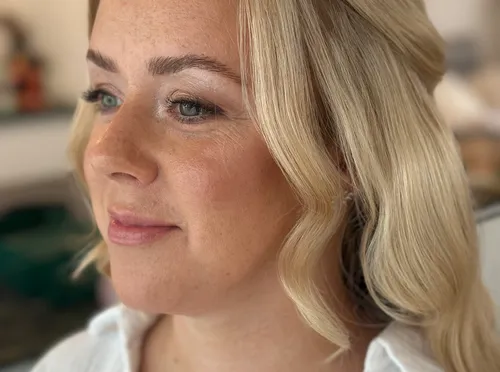 Frau mit blondem Haar lächelt drinnen.