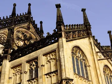 Gothic part of the building with decorations under a blue sky.