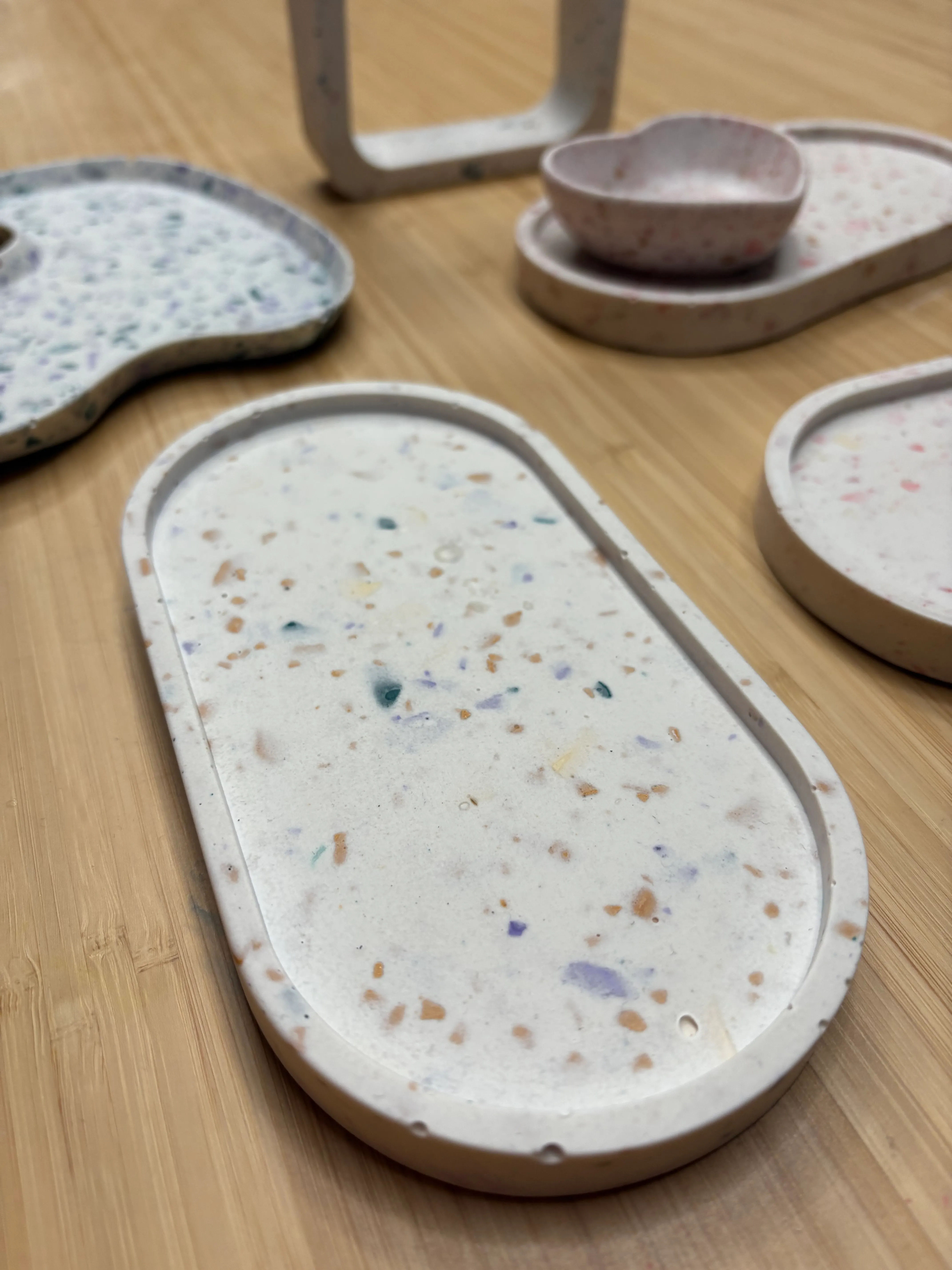 Colorful terrazzo trays on a wooden surface.