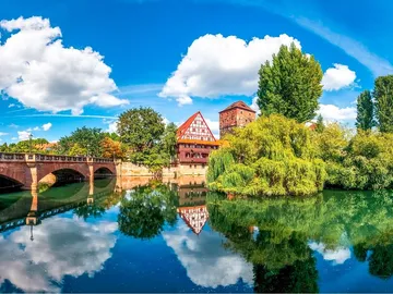 The historic building is reflected in the calm waters of the river.