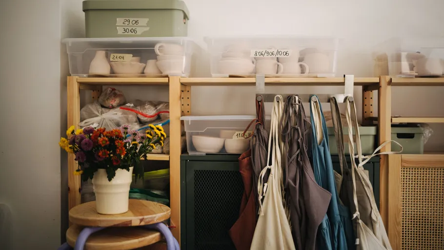 Shelving with pottery supplies and aprons hanging.