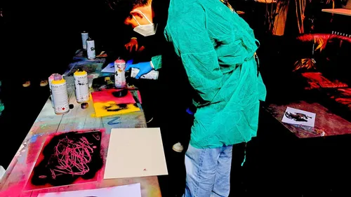 Person spray painting on canvases indoors.