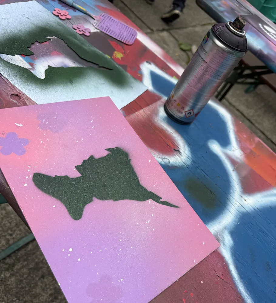 Sprühfarbe und Schablonen auf buntem Tisch.