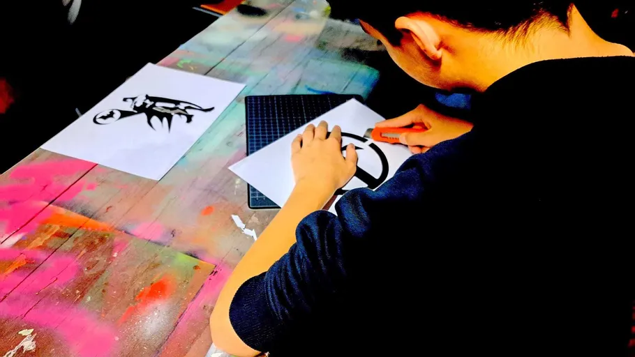 Person crafting stencil on colorful table.