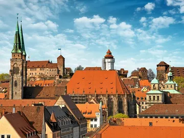 City view with red roofs, towers and blue sky.