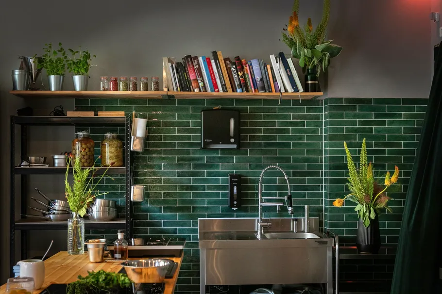 Kitchen with green tiles and books on shelf.
