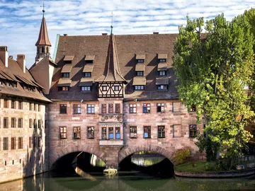 Historisches Gebäude mit Brücke über ruhigem Wasser.