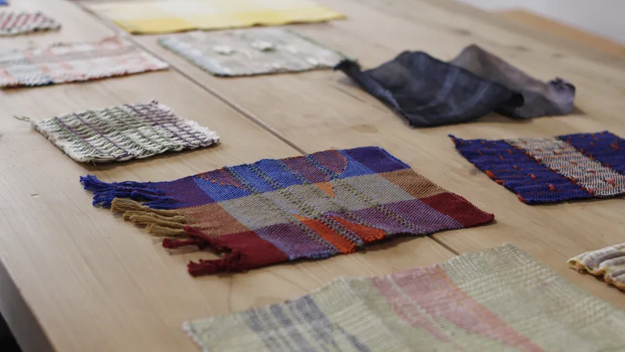 Colorful woven fabric samples on wooden table.