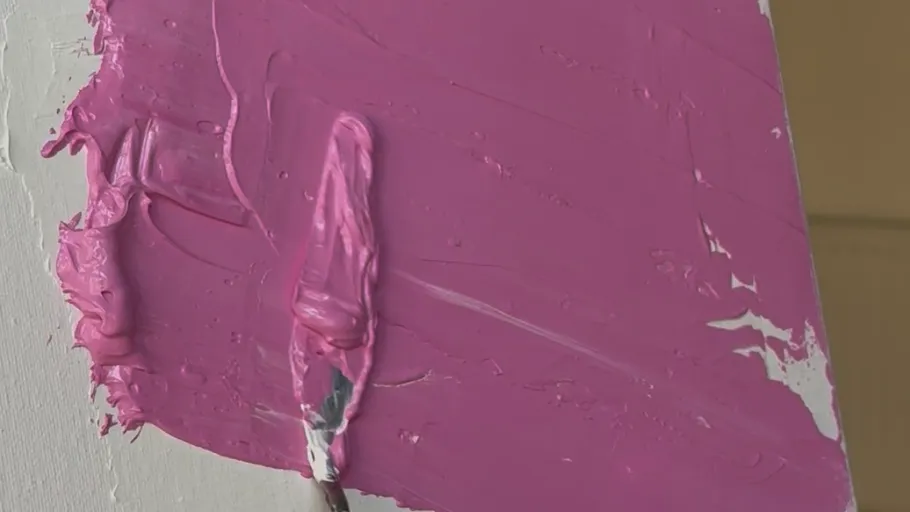 Pink paint smeared on canvas with knife.