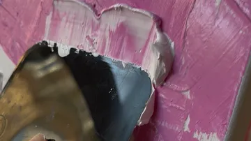 Maler verteilt rosa Farbe mit Spachtel.
