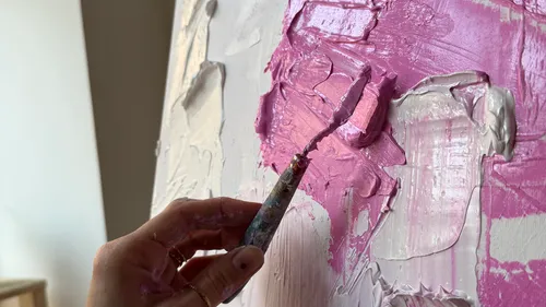 Hand verteilt rosa Farbe auf Leinwand.