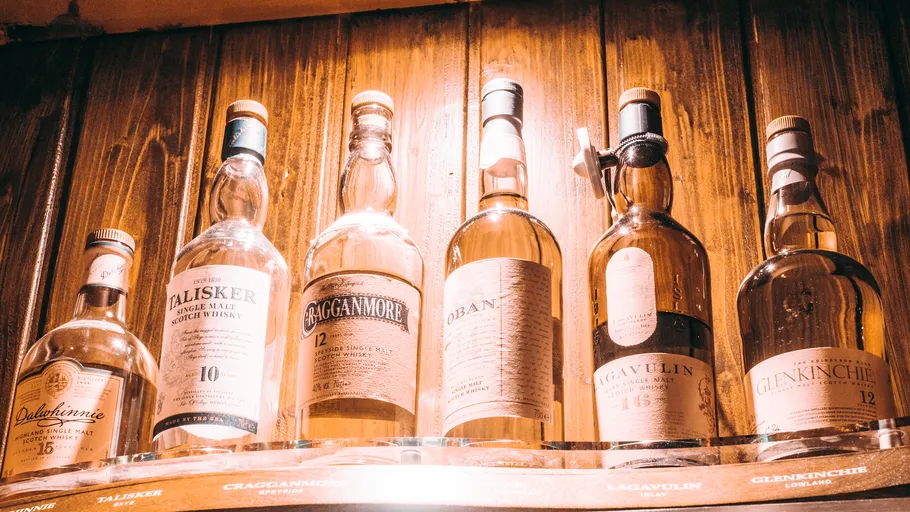 Whisky bottles displayed on wooden shelf.