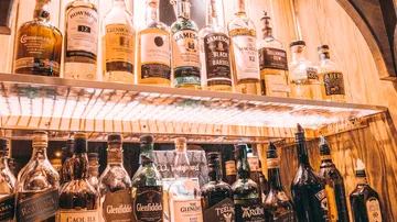 Verschiedene Whiskyflaschen auf Regalen ausgestellt.
