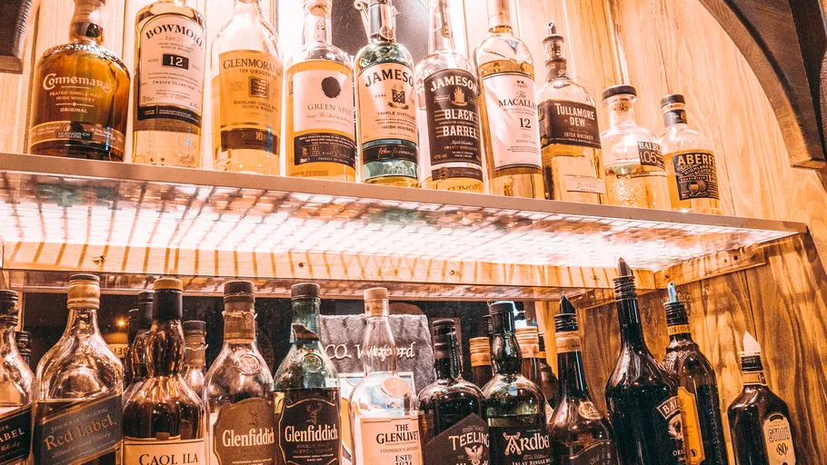 Verschiedene Whiskyflaschen auf Regalen ausgestellt.